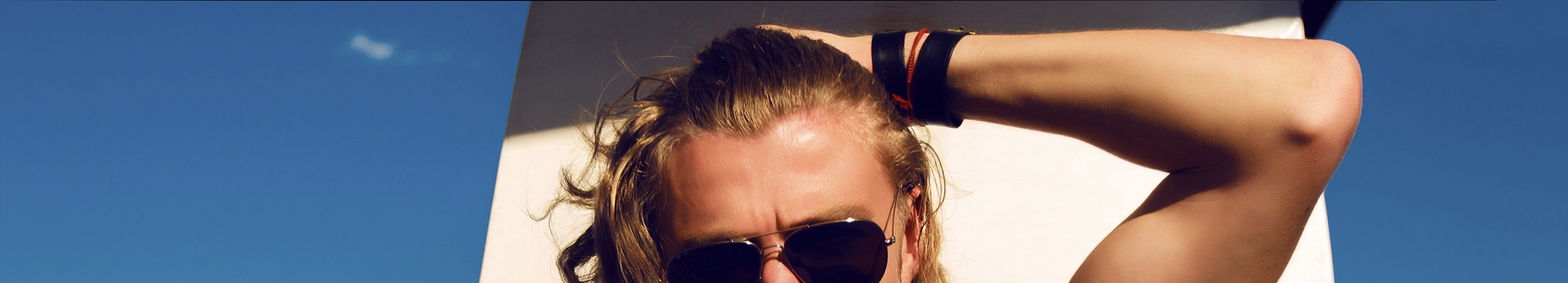 Tristan in the sunshine with sunglasses and his arm raised.